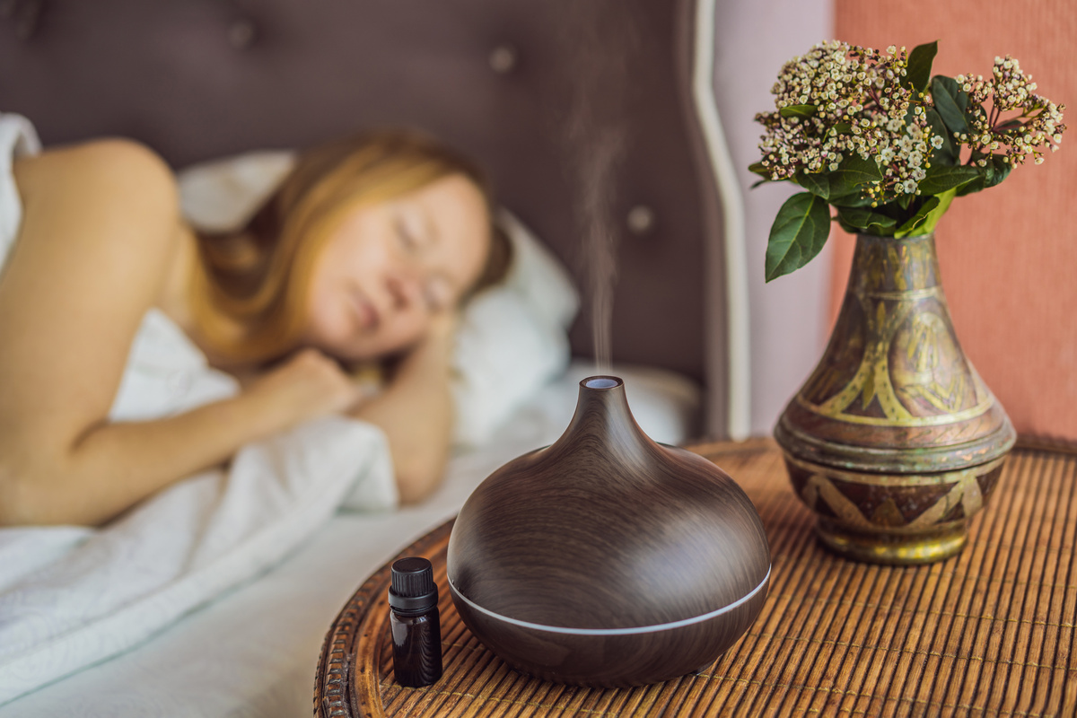 Aromatherapy Concept. Wooden Electric Ultrasonic Essential Oil Aroma Diffuser and Humidifier. Ultrasonic Aroma Diffuser for Home. Woman Resting at Home